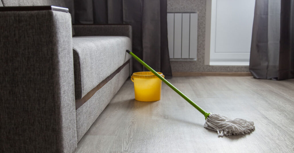 Living room with grey wood flooring and mop and bucket
