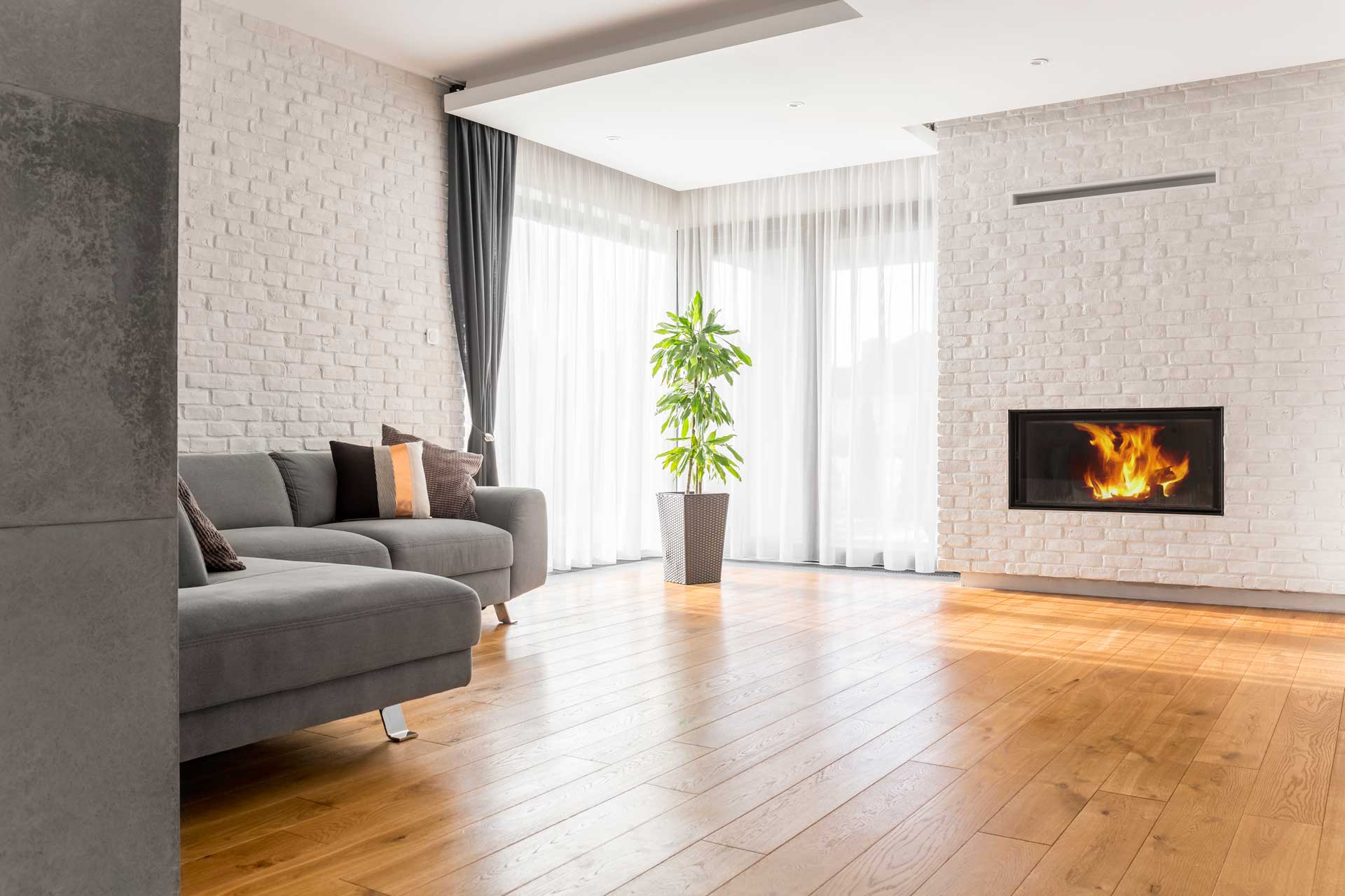 Living room with white brick walls and fireplace and light brown hardwood floors